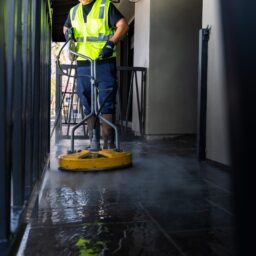 a man in a yellow vest is cleaning the floor