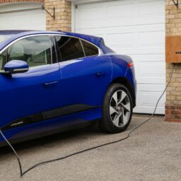 A blue electric car plugged in to a garage